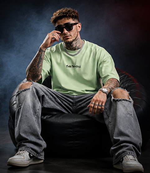 Model relaxing in the pastel green Beyond Vision oversized T-shirt with ripped grey jeans
