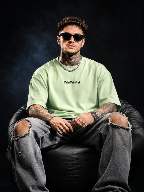 Seated model in the pastel green Beyond Vision oversized T-shirt with the small See Beyond chest script